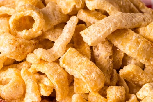 Delicious crispy pork rinds. A crisp salty snack on black glossy background