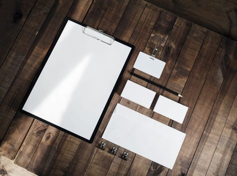 Photo of blank stationery set on wood background. Corporate identity template. Blank letterhead, business cards, envelope, badge, and pencil. Responsive design mock up. Top view.