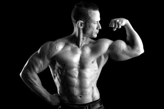 Power athletic man with great physique. Strong bodybuilder showing perfect body isolated in black.