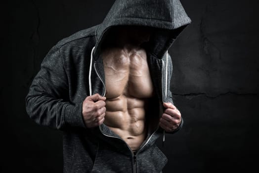 Power athletic man with hoodieshowing six pack, perfect abs over a grunge background