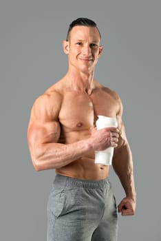 Powerful athletic man with great physique holding a gym bottle