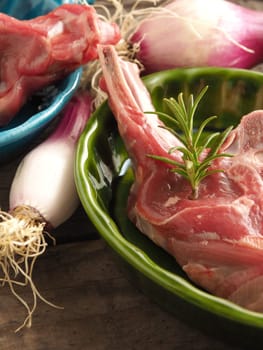 Raw lamb chop with rosemary in rustic bowls on wood