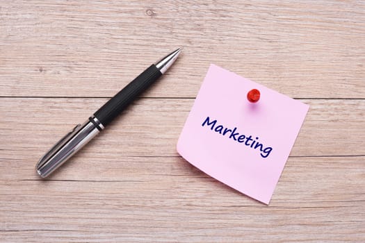 Concept marketing as a word on pink sticky note and ballpoint pen