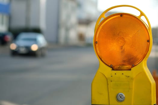 Warning lamp of a construction site in road traffic with a blurred vehicle