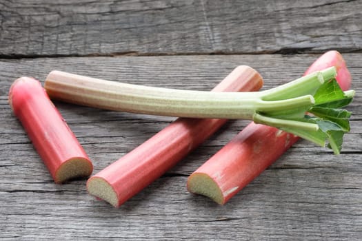 Red and green rhubarb in pieces on wood