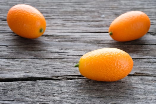 Kumquat fruits on rustic wood in backlight