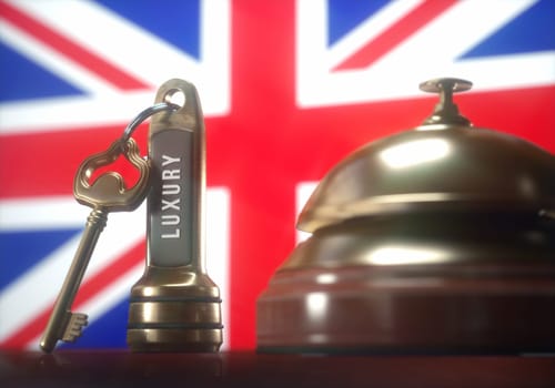Luxury hotel key and vintage golden bell of the United Kingdom on the wooden table of the lobby service.