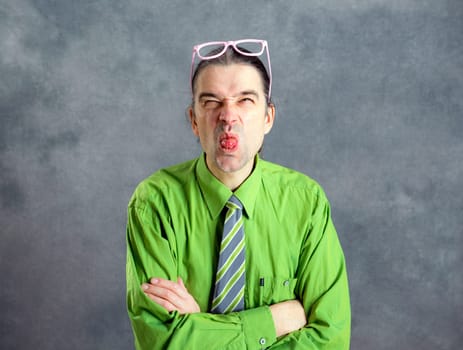 young man in green shirt pink glasses and necktie looking crazy in to the camera