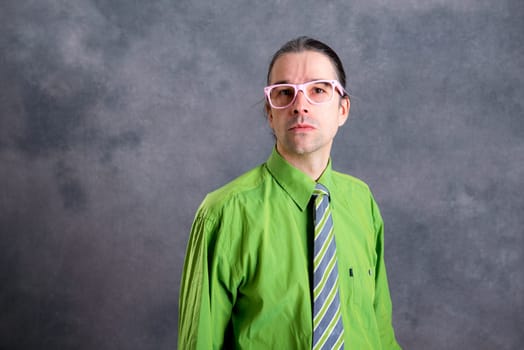 young man in green shirt pink glasses on head and necktie looking skeptical