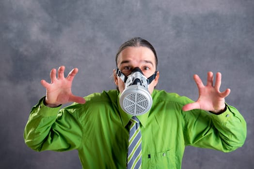 young business man in green shirt with gas mask in front of gray background