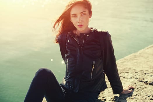 beautiful woman in jeans and jacket sitting on the breackwater.
