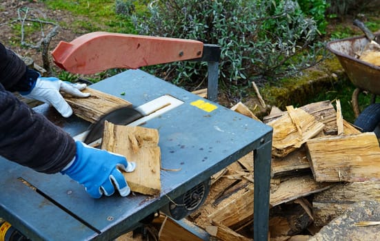 man making firewood with buzz saw in the garden