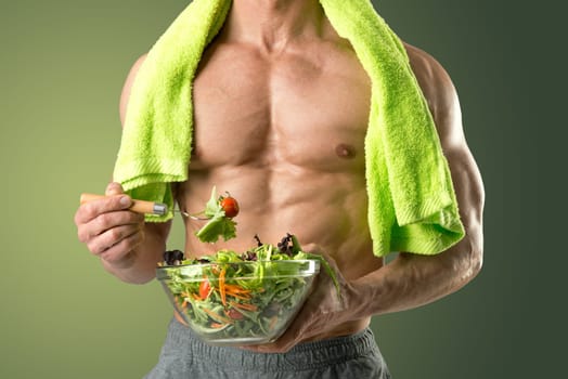 Powerful athletic man with great phisique eating a healthy salad.