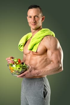 Powerful athletic man with great phisique eating a healthy salad.