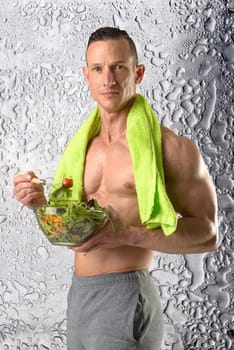 Powerful athletic man with great phisique eating a healthy salad.