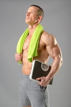 Powerful athletic man with great phisique holding a weight scale.