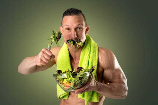 Powerful athletic man with great phisique eating a healthy salad.