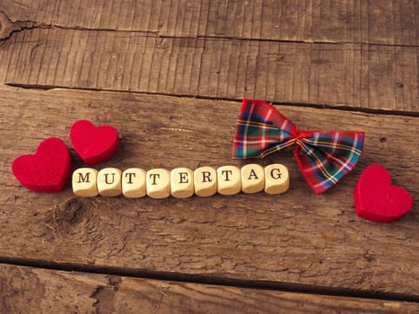 German Mothers Day background with wooden dices and red heart shapes