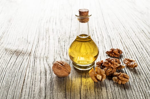 Walnut oil in a glass bottle on a wooden background