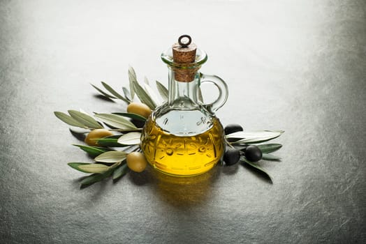 Olive oil and olive branch on the gray table