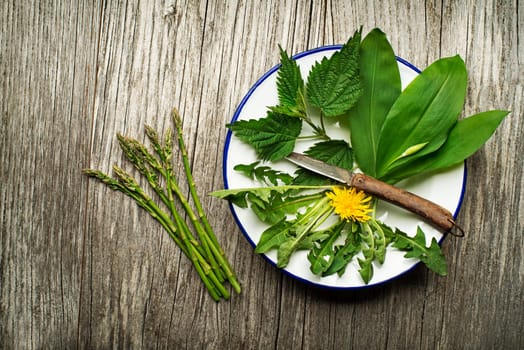 Spring food nettle, dandelion, wild garlic and asparagus on wooden background