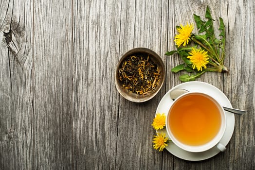 Cup of healthy dandelion tea on wooden background. Herbal medicine.