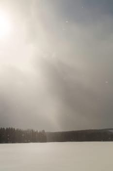 Lake with Forest with Snow Falling and a cloudy sky.
