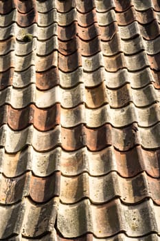 closeup of vintage tile roof with light and dark brick. The roof is old and many of the tiles are cracked