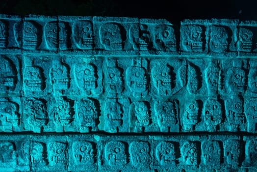 Platform of Skulls known as Tzompantli at night with blue colored light in Chichen Itza, Mexico