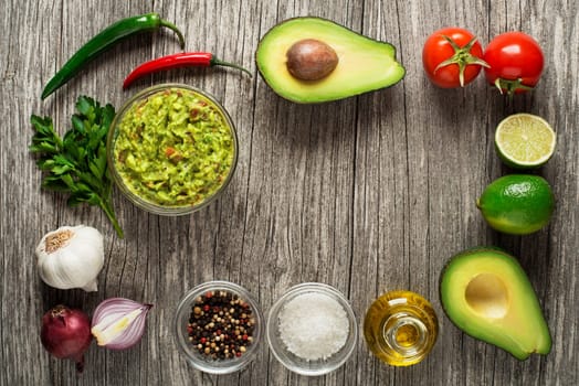 Avocado guacamole with fresh ingredients on wooden table