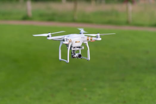 OLDENZAAL, NETHERLANDS - JUNE 19, 2016: DJI Phantom drone with camera attached flying low above the grass