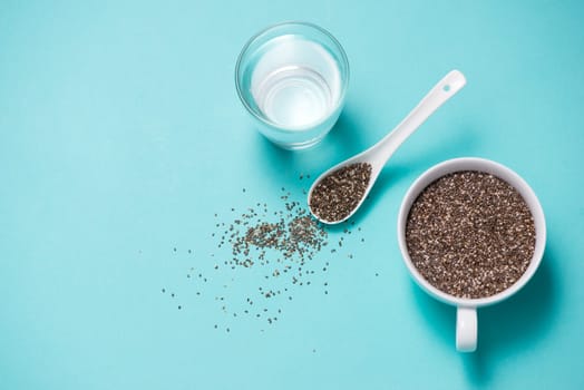 Glass of water with cup of healthy chia seeds and spoon. Text space.