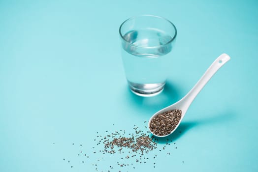 Glass of water and healthy chia seeds in a spoon. Text space.