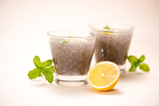 Selective focus of chia seeds drink with water in transparent glass with lemon balm.