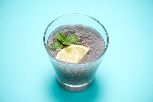 Selective focus of chia seeds drink with water in transparent glass with lemon balm.