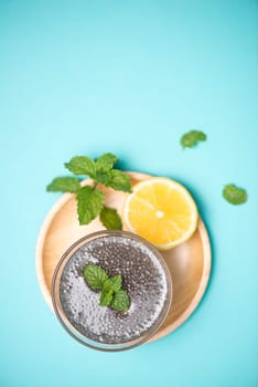 Selective focus of chia seeds drink with water in transparent glass with lemon balm.