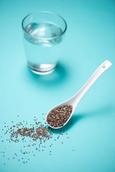 Glass of water and healthy chia seeds in a spoon. Text space.