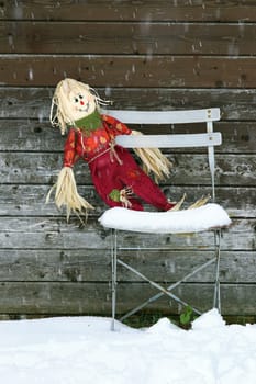 The forgotten doll on the old chair in winter