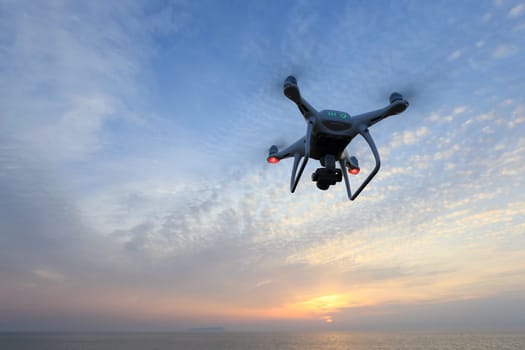 KAGAWA, JAPAN - APRIL 21, 2017: Remote controlled drone Dji Phantom4Pro equipped with high resolution video camera flying above the sea against a sunset sky.