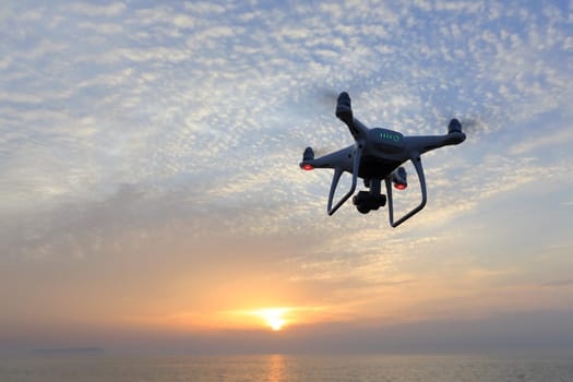 KAGAWA, JAPAN - APRIL 21, 2017: Remote controlled drone Dji Phantom4Pro equipped with high resolution video camera flying above the sea against a sunset sky.