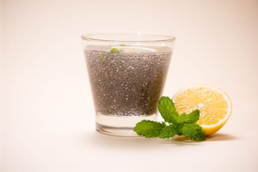 Selective focus of chia seeds drink with water in transparent glass with lemon balm.