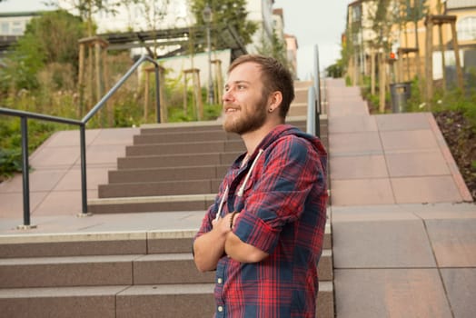 young bearded man in checkered shirt standing on stairs