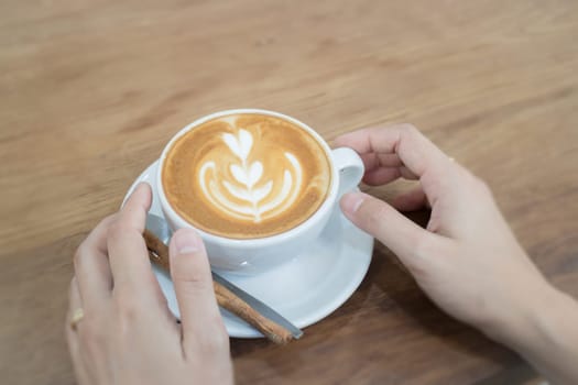 Hand On Hot Cup Of Coffee Latte, stock photo