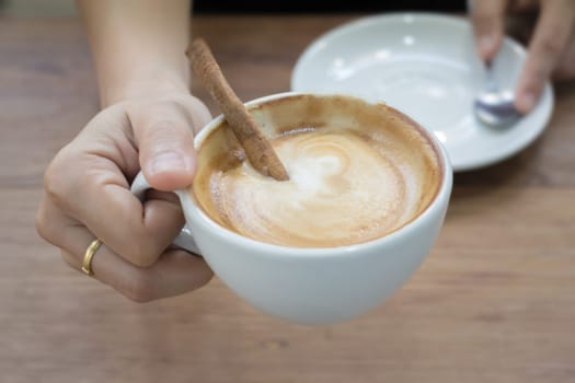 Hand On Hot Cup Of Coffee Latte, stock photo