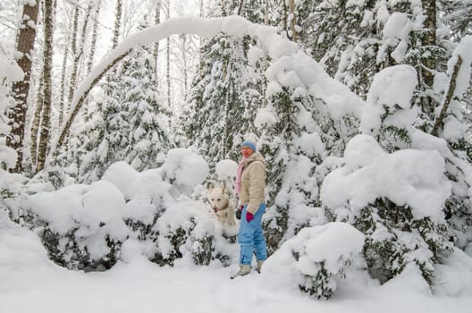 A woman with a dog in a snow-covered winter forest