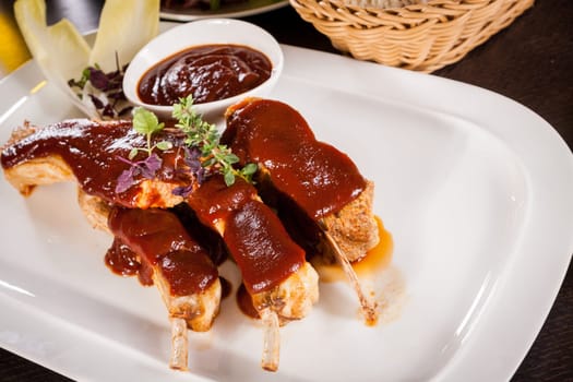 Grilled pork ribs Spareribs with barbecue sauce marinade and herb salad on a plate