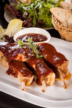 Grilled pork ribs Spareribs with barbecue sauce marinade and herb salad on a plate