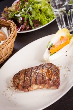 Succulent grilled beef fillet steak with homemade herb butter on a plate isolated against a white background
