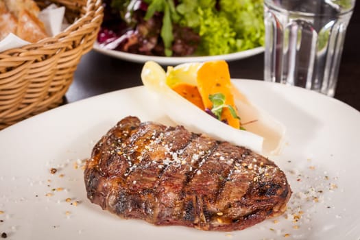 Succulent grilled beef fillet steak with homemade herb butter on a plate isolated against a white background