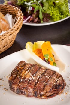 Succulent grilled beef fillet steak with homemade herb butter on a plate isolated against a white background